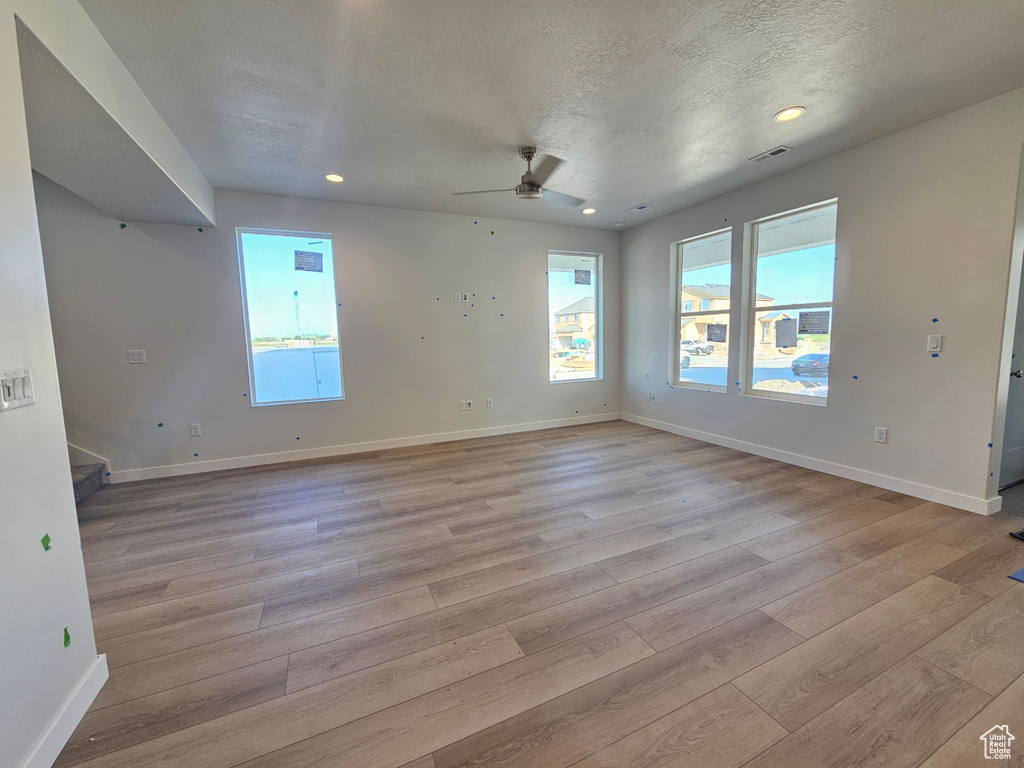 Empty room with light wood-style floors, stairs, a ceiling fan, recessed lighting, and a textured ceiling
