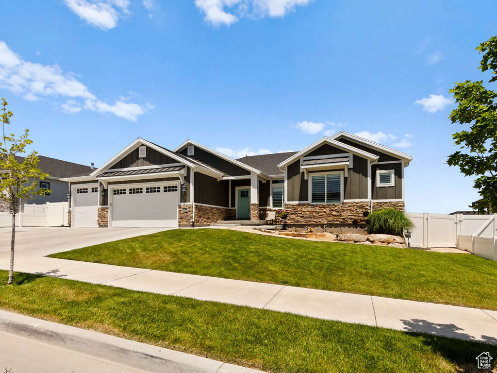 Craftsman-style house featuring board and batten siding, stone siding, an attached garage, a gate, and driveway