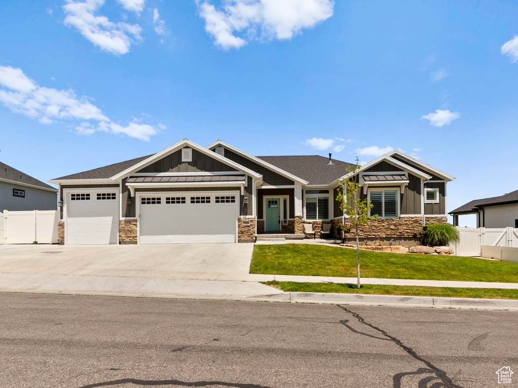 Craftsman inspired home featuring board and batten siding, stone siding, an attached garage, and concrete driveway