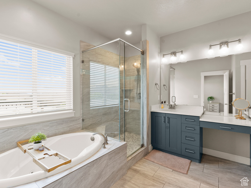 Bathroom with vanity, a tub with jets, and a stall shower