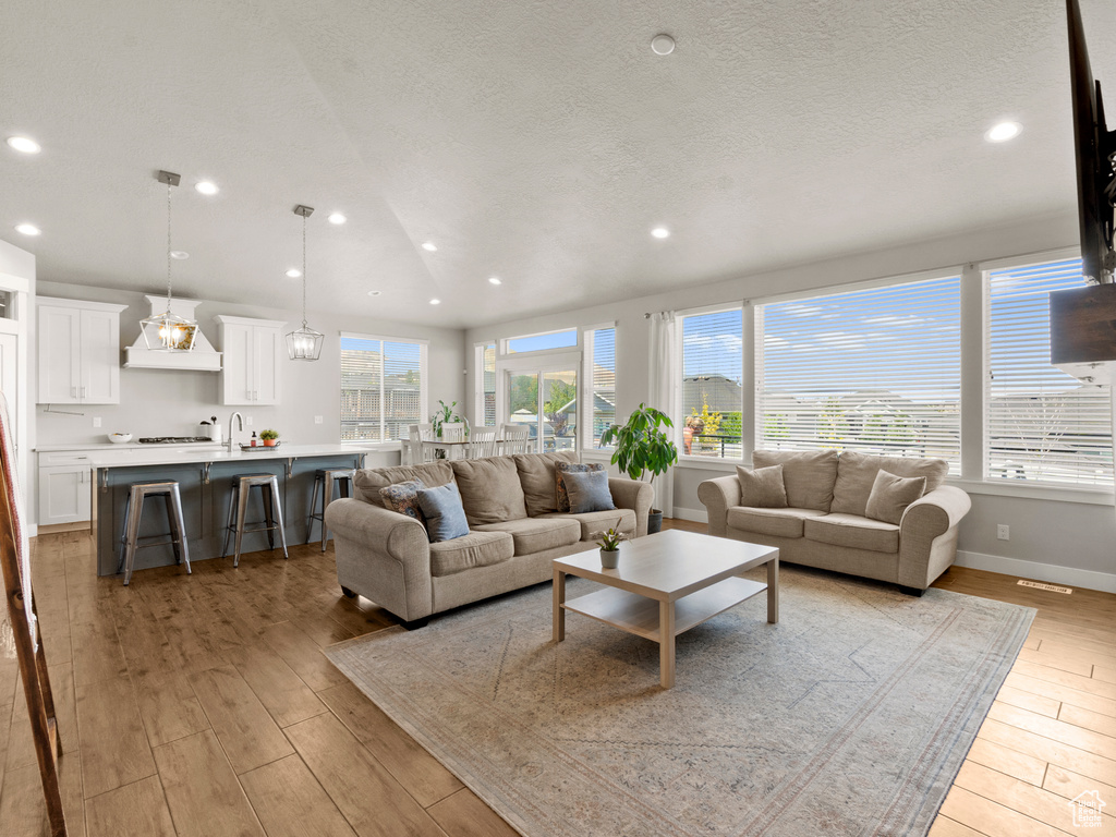 Living room with recessed lighting, light wood-style flooring, and a textured ceiling