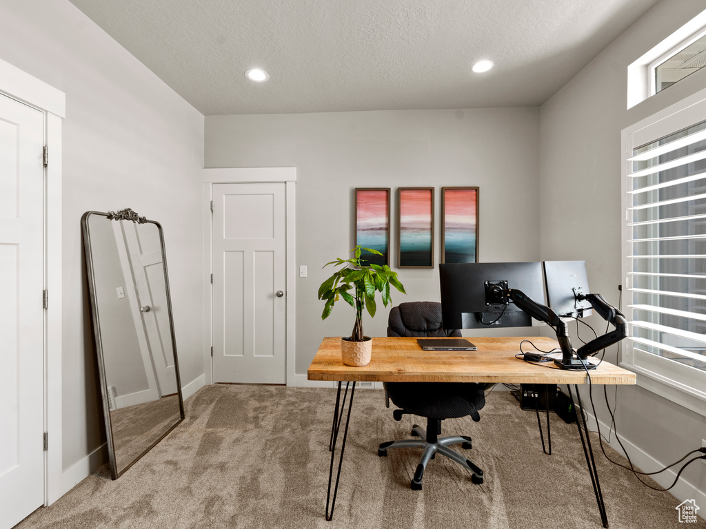 Office space featuring light colored carpet, plenty of natural light, a textured ceiling, and recessed lighting