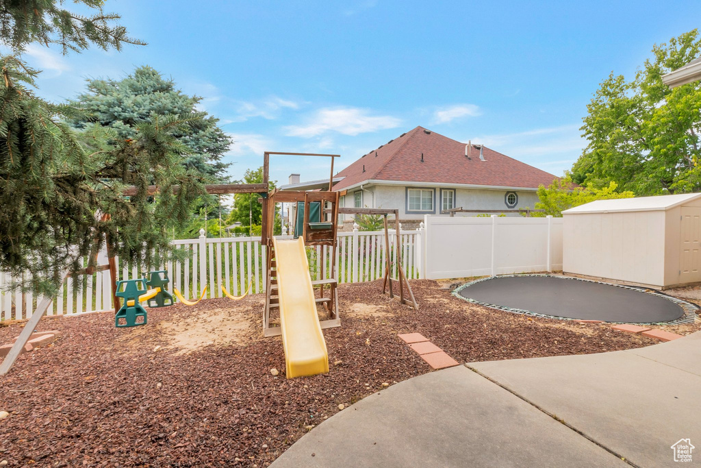 View of playground with a trampoline, a storage shed, and a fenced backyard