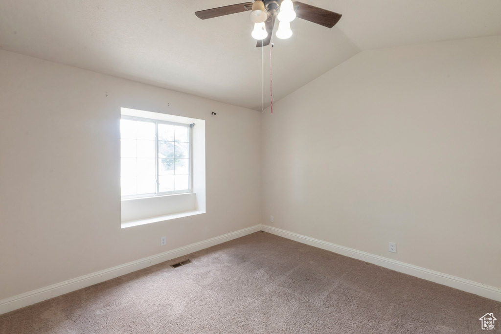 Empty room with a ceiling fan, carpet, and lofted ceiling