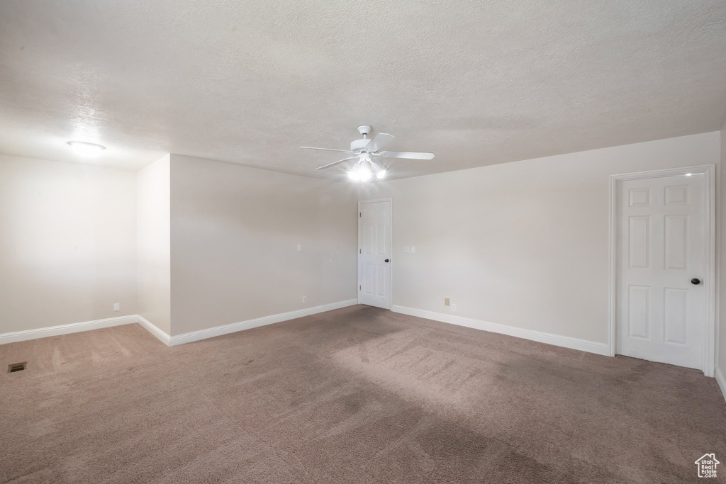 Empty room featuring a ceiling fan, carpet flooring, and a textured ceiling