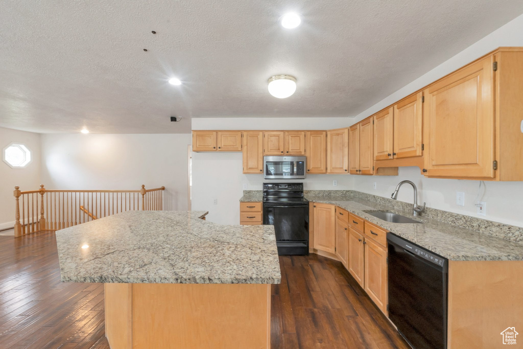 Kitchen featuring dishwasher, stainless steel microwave, range, light brown cabinets, and a center island