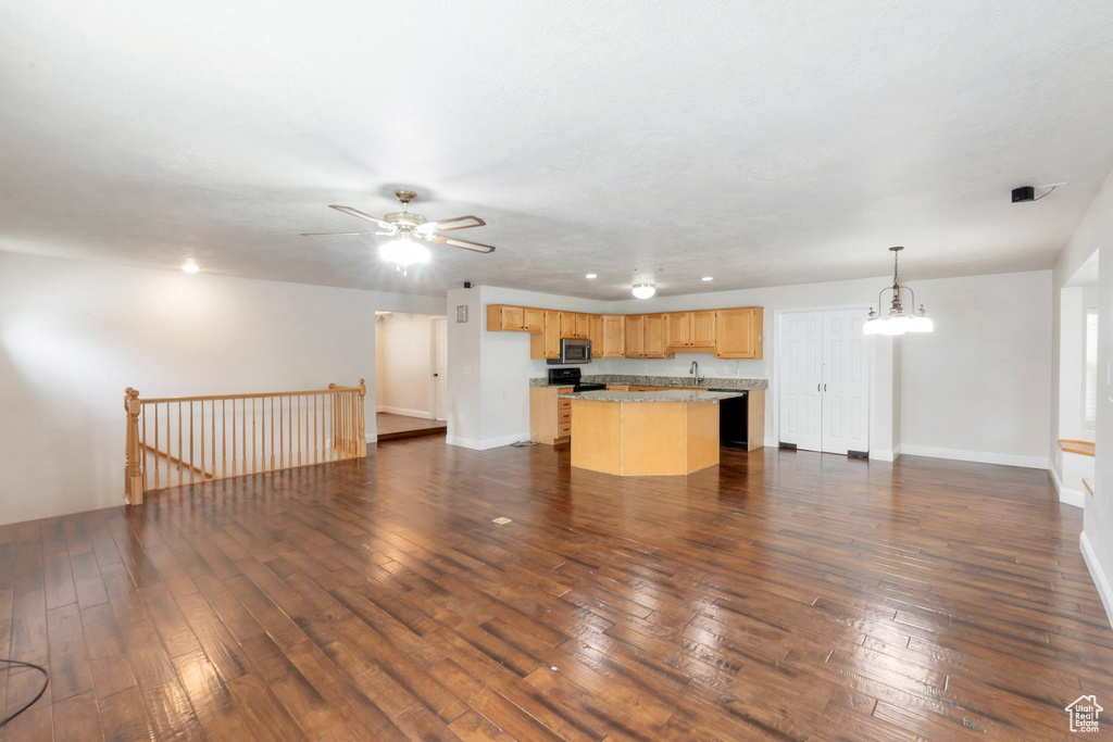 Unfurnished living room featuring dark wood-style floors, a ceiling fan, and a chandelier
