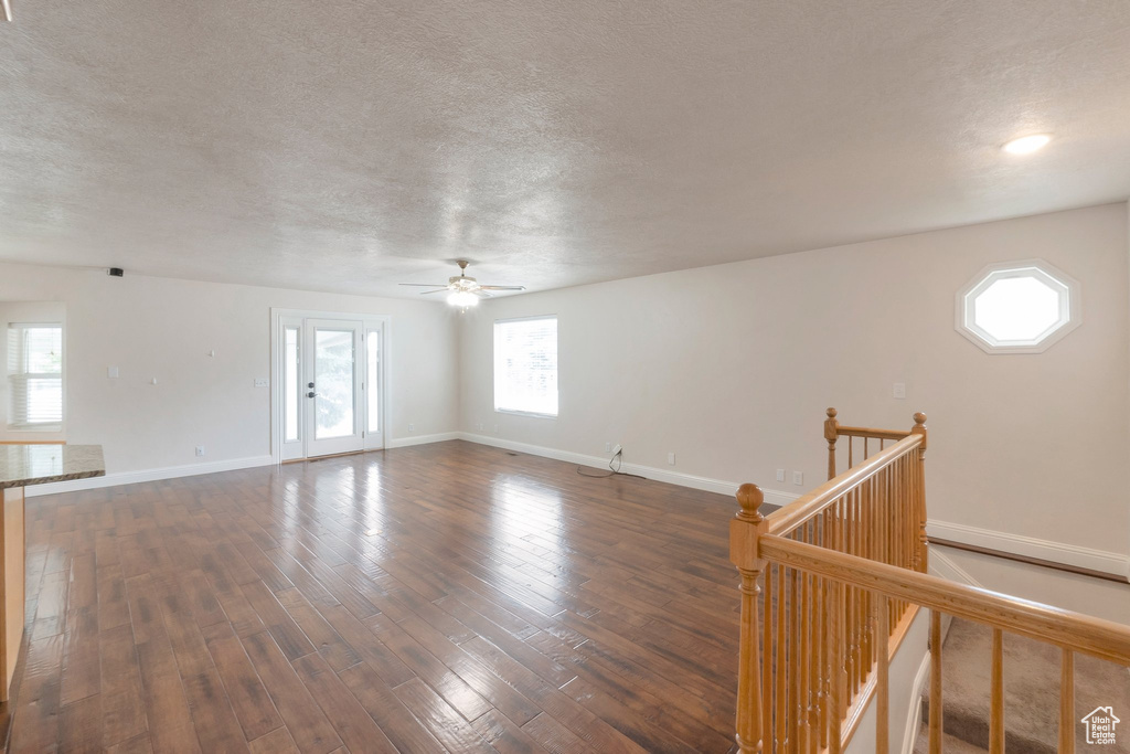 Unfurnished room featuring a textured ceiling, ceiling fan, and dark wood-style floors