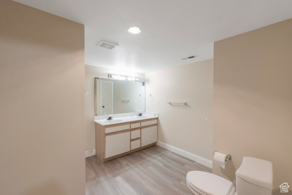 Bathroom featuring wood finished floors, double vanity, and recessed lighting