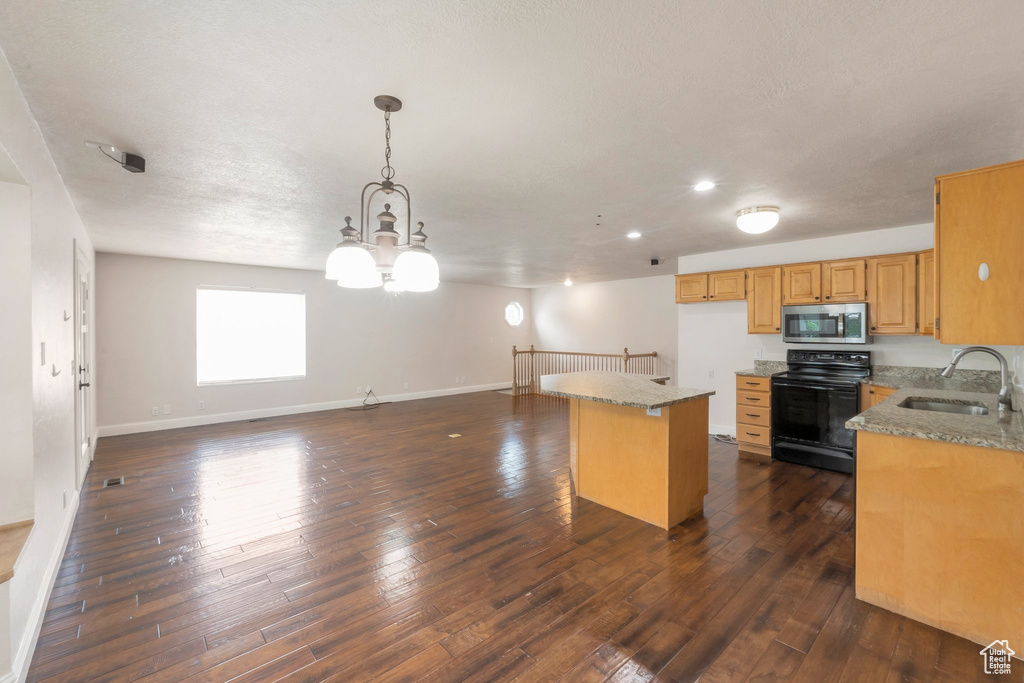 Kitchen with black range with electric cooktop, stainless steel microwave, light stone counters, open floor plan, and dark wood finished floors