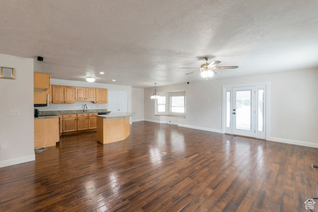 Kitchen featuring ceiling fan, a textured ceiling, a center island, open floor plan, and light countertops