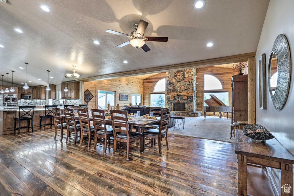 Dining space with lofted ceiling, dark wood-style floors, ceiling fan, wooden walls, and recessed lighting