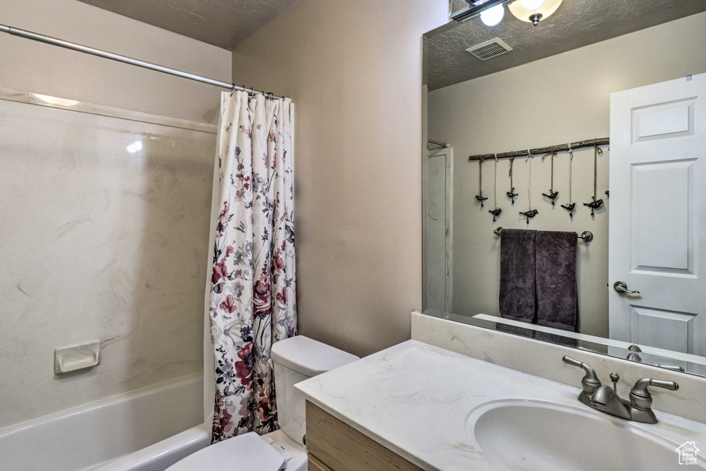 Bathroom featuring vanity, shower / bath combo, and a textured ceiling