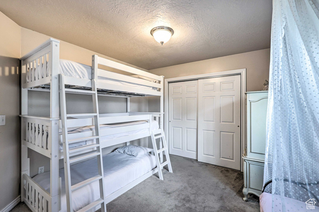 Bedroom featuring carpet floors, a closet, and a textured ceiling