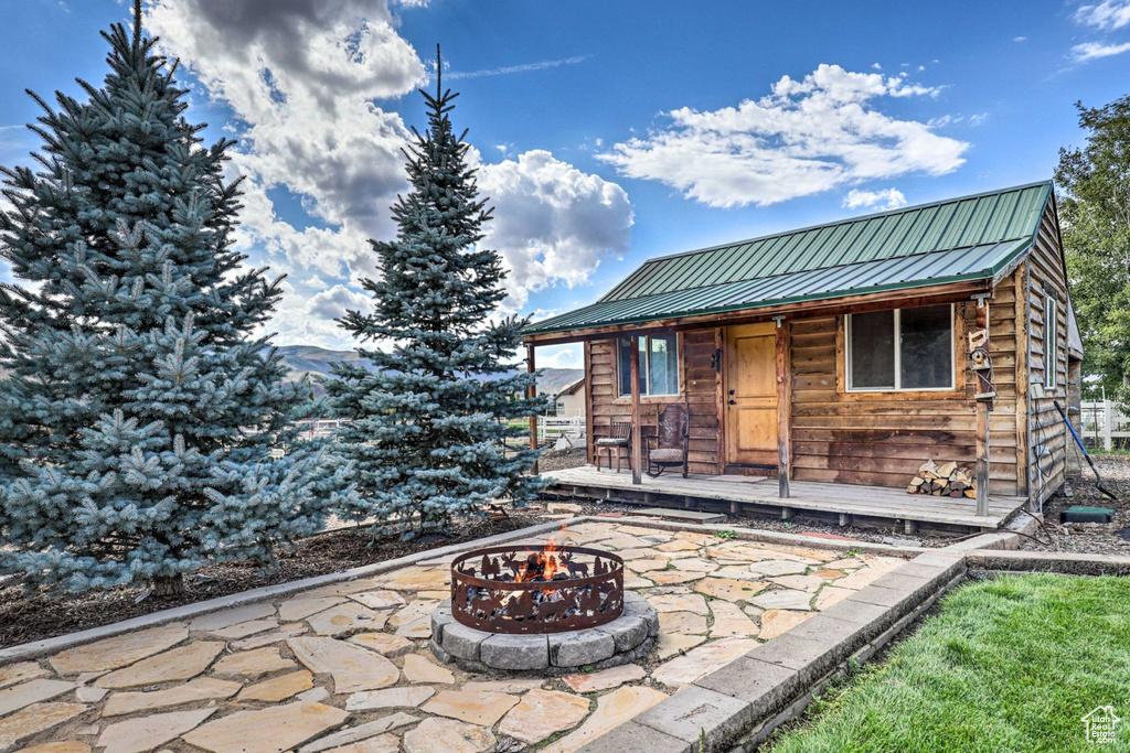 View of patio with an outdoor fire pit and an outdoor structure