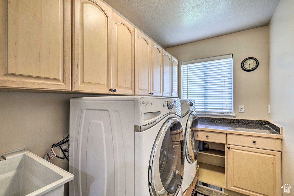 Washroom with washer and clothes dryer, cabinet space, and a textured ceiling