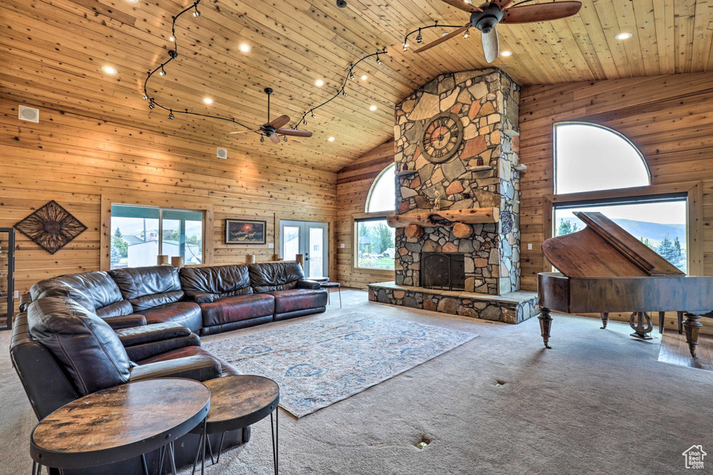 Carpeted living area with ceiling fan, wooden walls, healthy amount of natural light, high vaulted ceiling, and wood ceiling