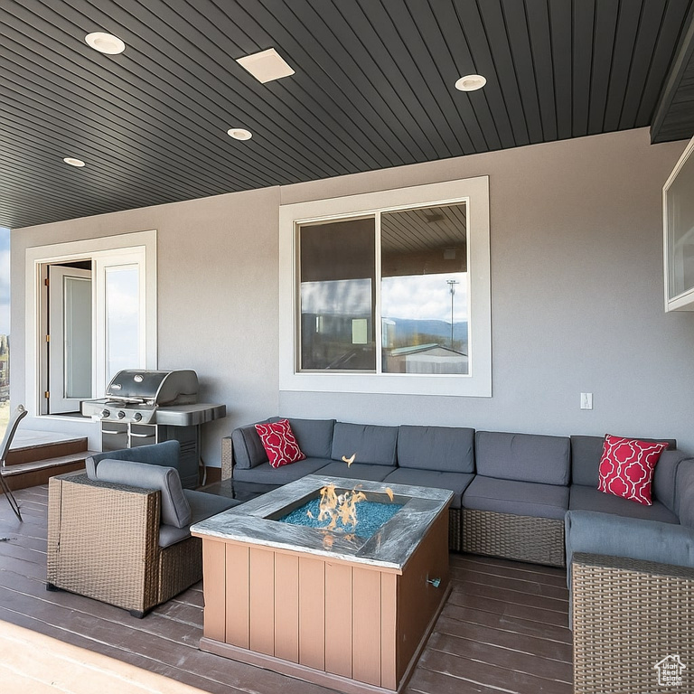 Wooden terrace with an outdoor living space with a fire pit and area for grilling