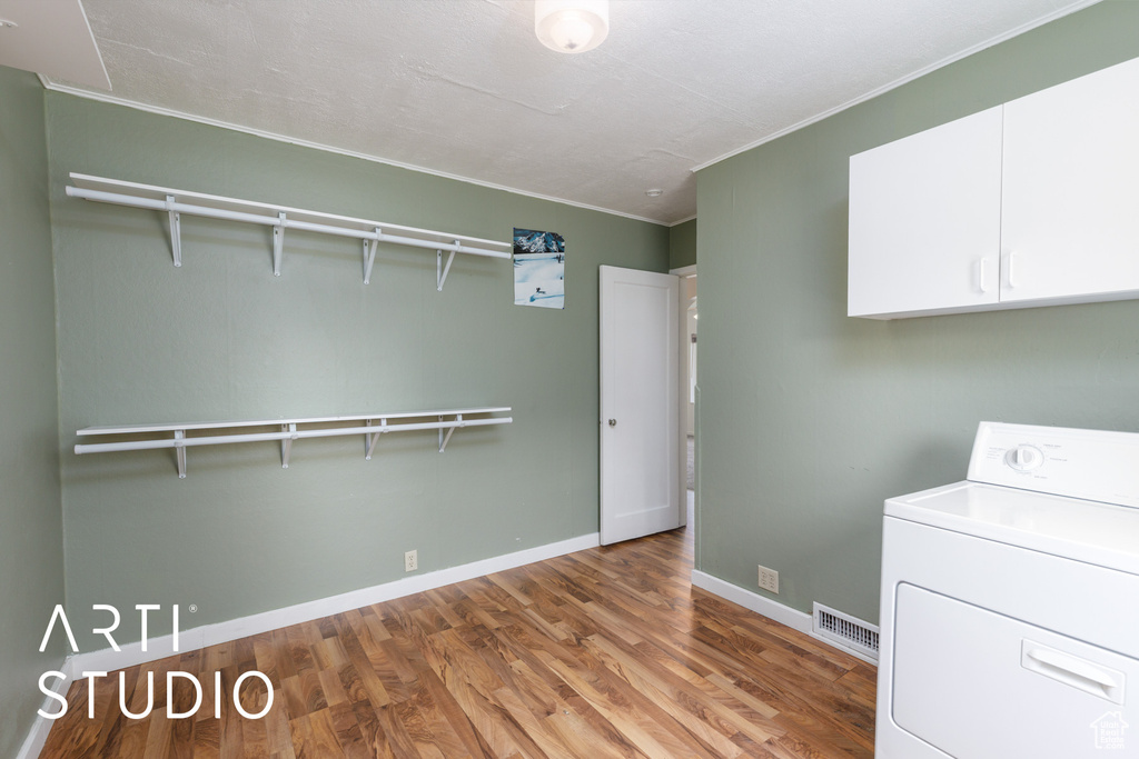 Laundry room featuring washer / dryer, crown molding, wood finished floors, and cabinet space