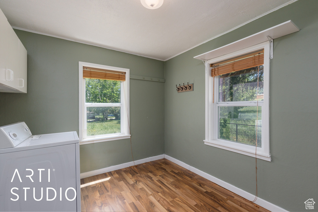 Laundry room with washer / dryer, cabinet space, dark wood finished floors, and ornamental molding