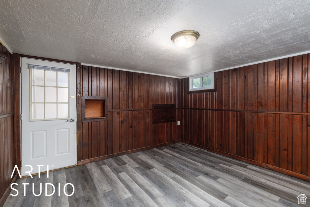 Unfurnished room with wood finished floors, a textured ceiling, and wooden walls