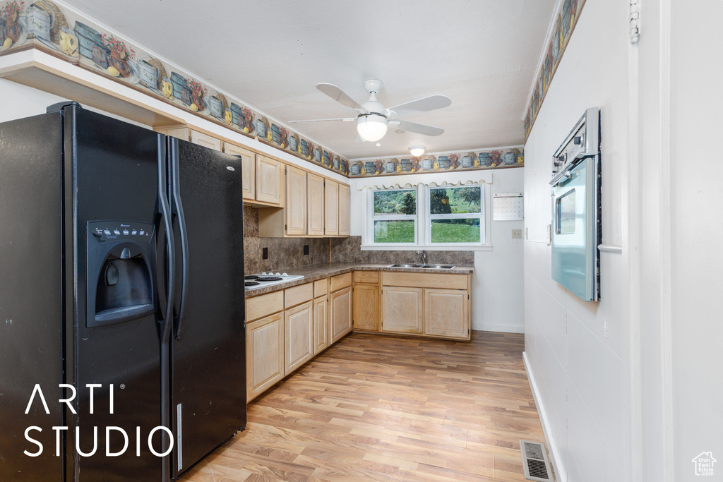 Kitchen featuring black fridge with ice dispenser, light brown cabinets, a ceiling fan, and light wood-style flooring