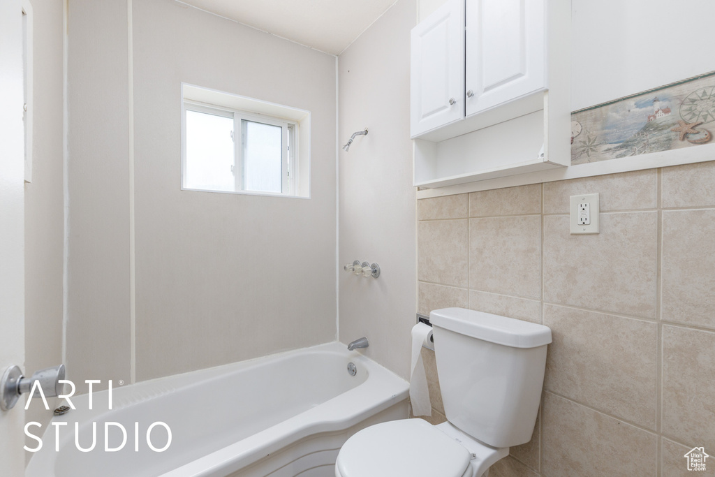 Full bath featuring tile walls and shower / washtub combination