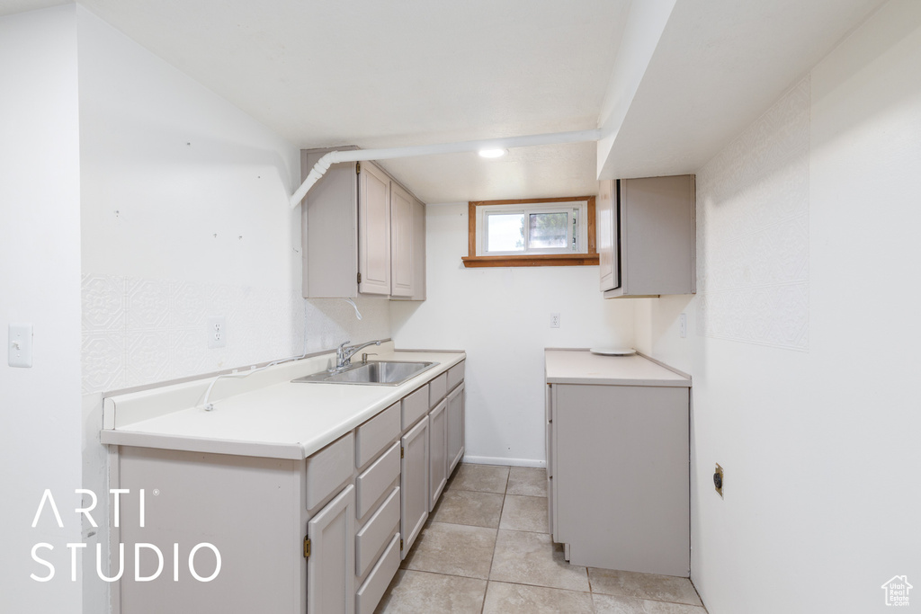Laundry area with a sink and light tile patterned flooring