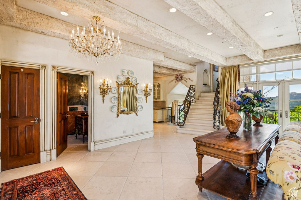 Entrance foyer with beamed ceiling, light tile patterned flooring, a chandelier, french doors, and stairs