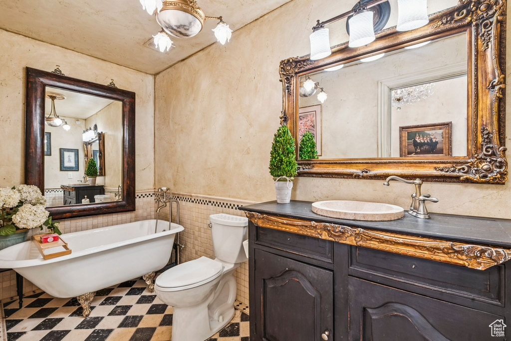 Bathroom with a freestanding tub, vanity, tile patterned floors, a wainscoted wall, and tile walls