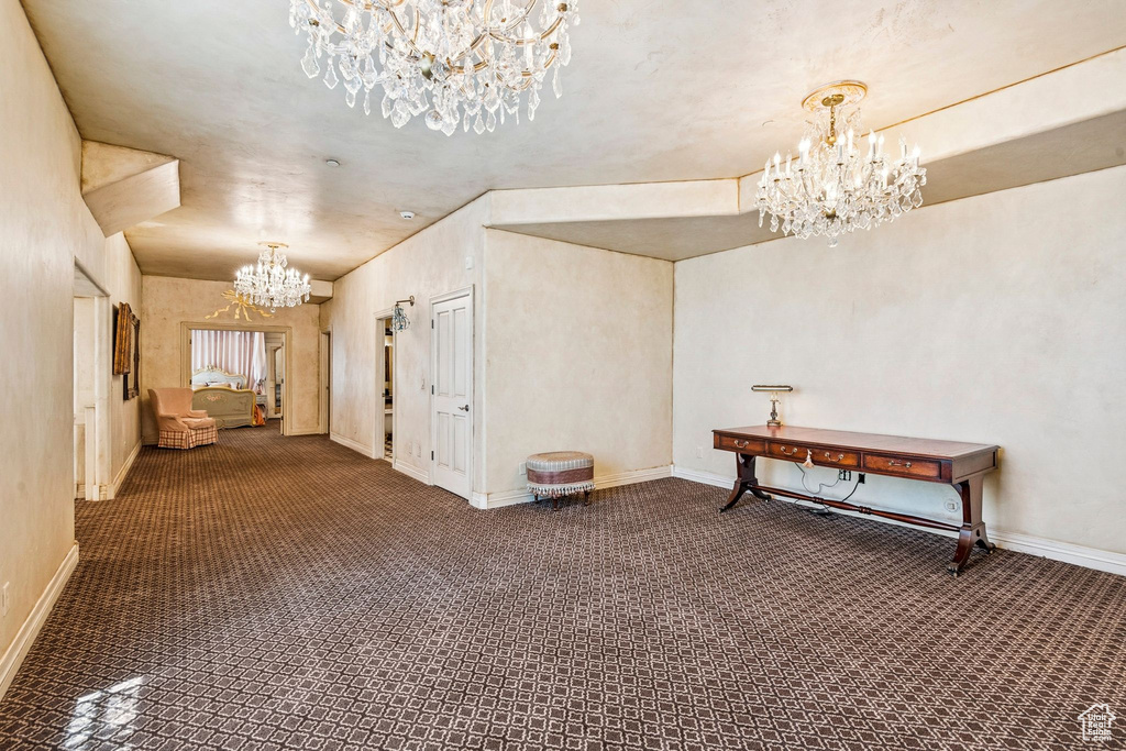 Hallway with a chandelier and carpet flooring