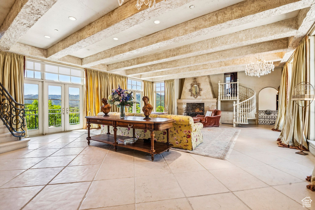 Living room with stairway, light tile patterned floors, a high end fireplace, beamed ceiling, and a chandelier