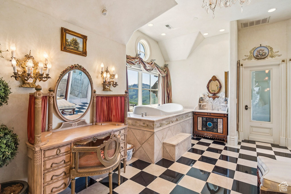 Bathroom with a chandelier, vaulted ceiling, a bath, and recessed lighting