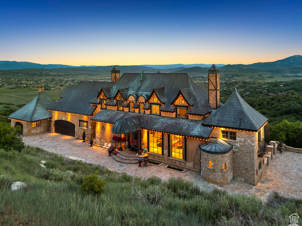 Back of property featuring a chimney, a mountain view, an attached garage, and stone siding