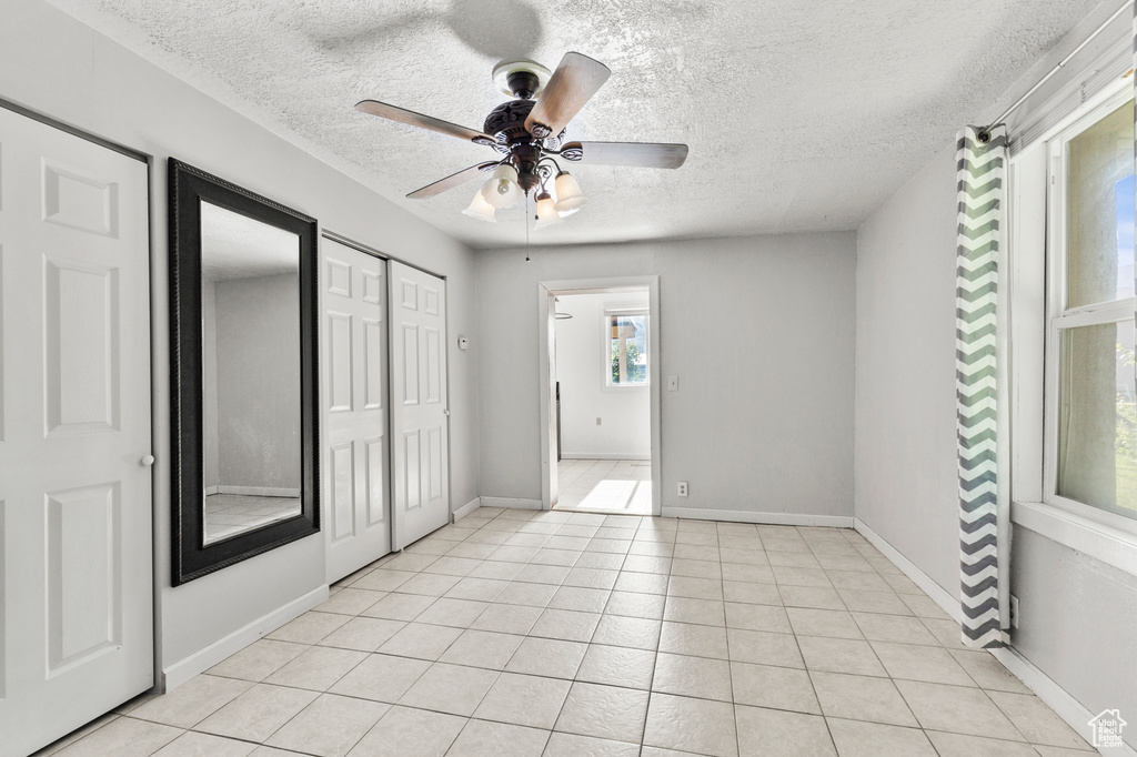 Unfurnished bedroom with a textured ceiling, a ceiling fan, and light tile patterned floors