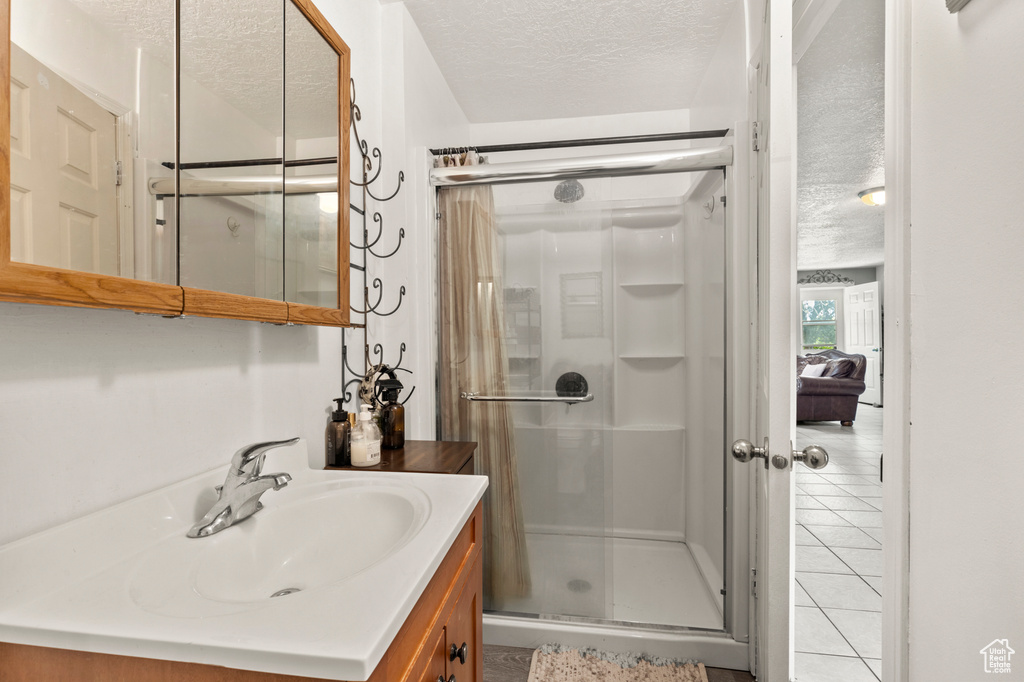 Bathroom featuring a textured ceiling, a stall shower, vanity, and tile patterned flooring