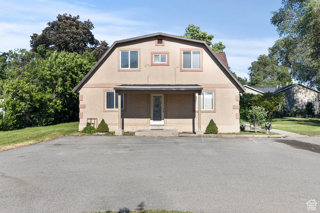 Dutch colonial with stucco siding and a front lawn