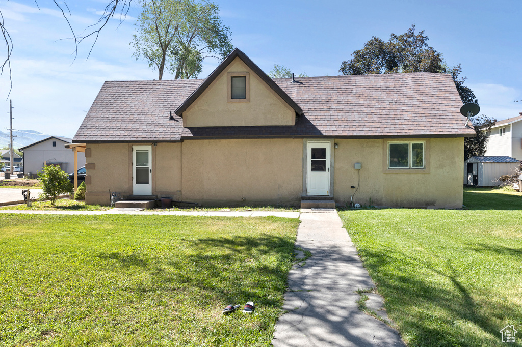 Tudor house featuring stucco siding, a front lawn, and a shingled roof