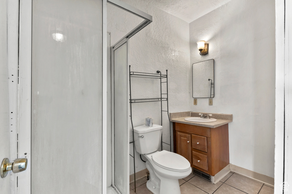 Full bath with vanity, a stall shower, tile patterned flooring, and a textured wall