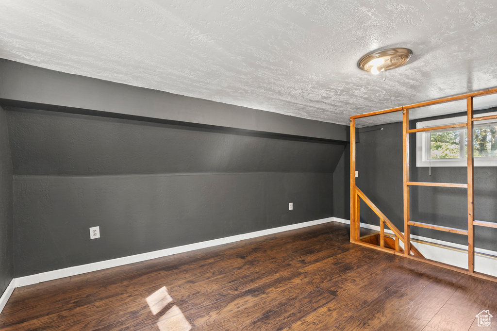 Bonus room with a textured ceiling, wood-type flooring, and lofted ceiling