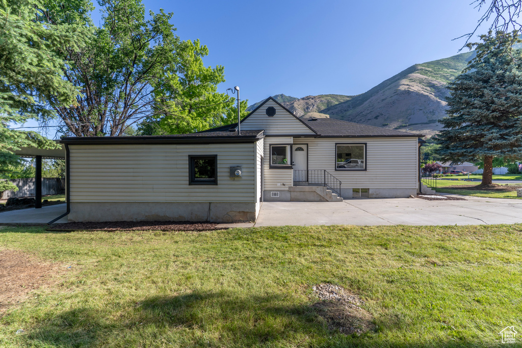 View of front of house featuring a mountain view, a front lawn, and a patio area