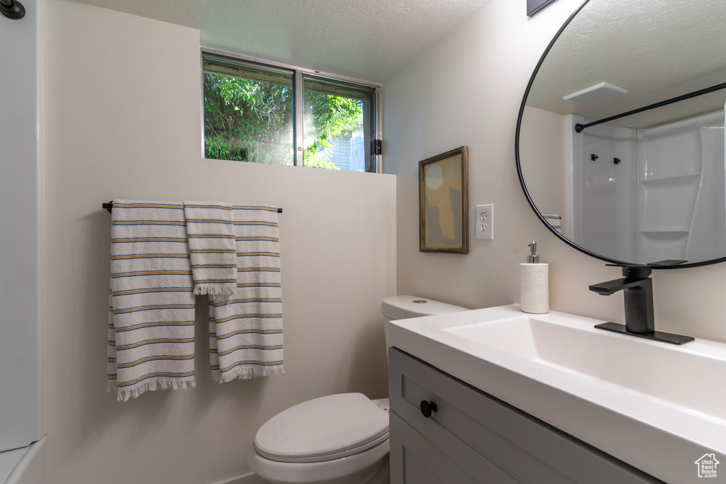 Bathroom with vanity, a textured ceiling, and a shower