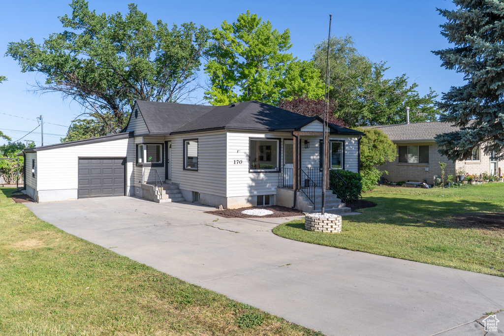 View of front of house featuring driveway, an attached garage, and a front yard