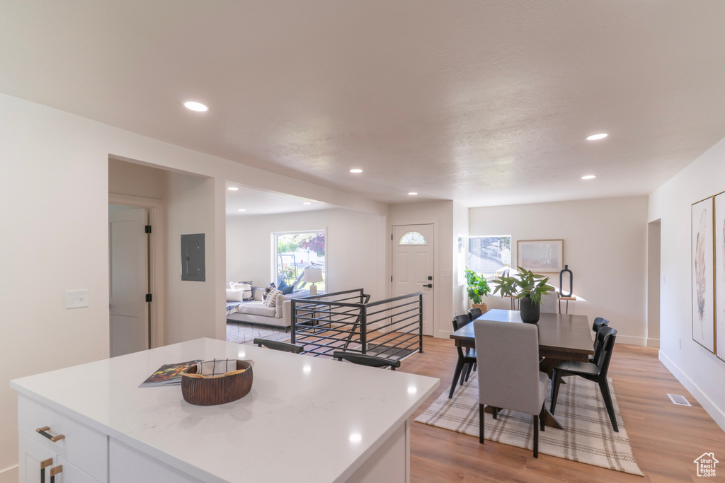 Kitchen with light countertops, recessed lighting, white cabinetry, light wood-style floors, and electric panel
