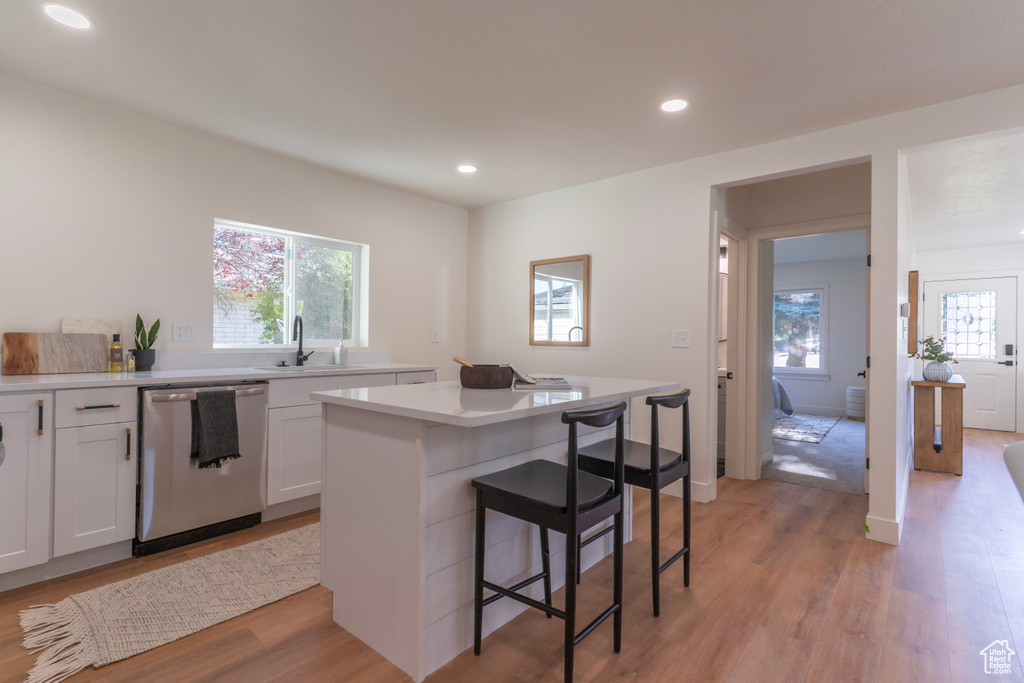 Kitchen featuring dishwasher, a breakfast bar, a kitchen island, healthy amount of natural light, and recessed lighting