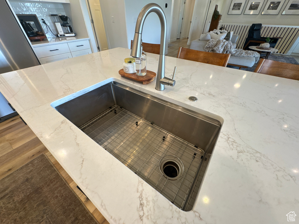 Kitchen view of light stone countertops, wood finished floors, white cabinetry, and stainless steel refrigerator with ice dispenser