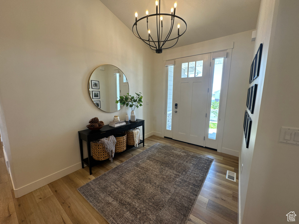 Foyer featuring a chandelier, light wood finished floors, and vaulted ceiling