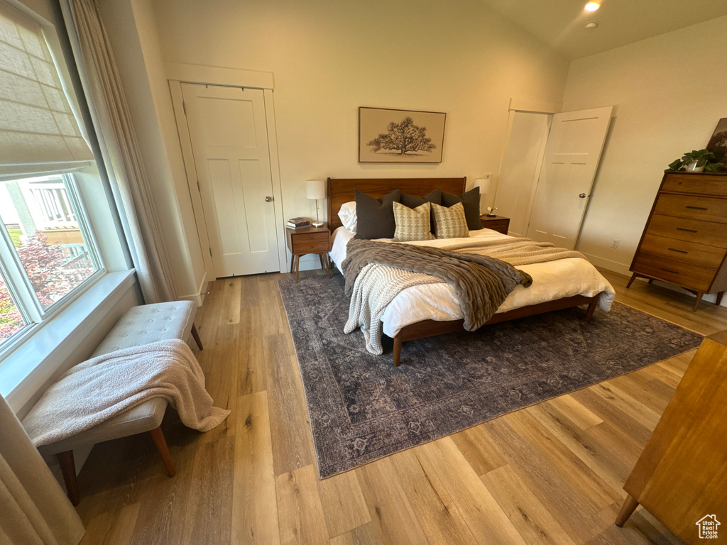 Bedroom with light wood finished floors and a towering ceiling