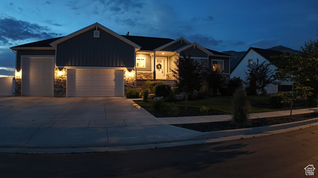Ranch-style home with an attached garage, stone siding, driveway, and board and batten siding