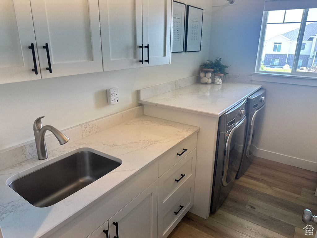 Kitchen featuring separate washer and dryer, white cabinetry, wood finished floors, and light stone counters